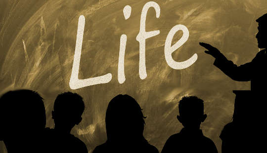 học sinh trong lớp học với từ "Life" được viết trên bảng đen