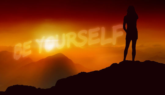 outline of a woman standing on a hilltop with the words BE YOURSELF brightly lit in the sky 