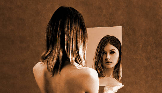 vrouw kijkt naar zichzelf in de spiegel