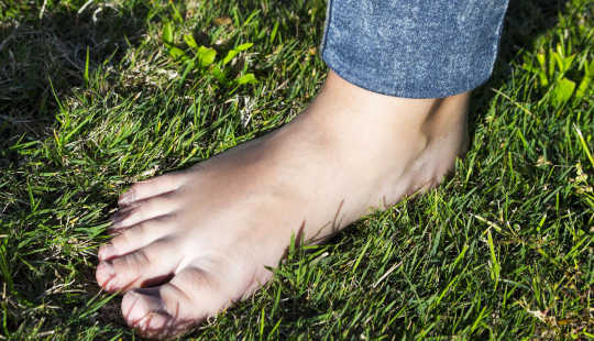 ภาพเท้าเปล่าของคนยืนอยู่บนพื้นหญ้า
