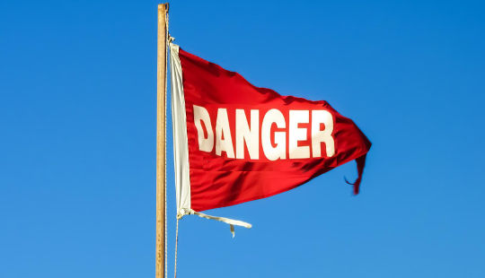 Bendera bahaya merah berkibar tertiup angin