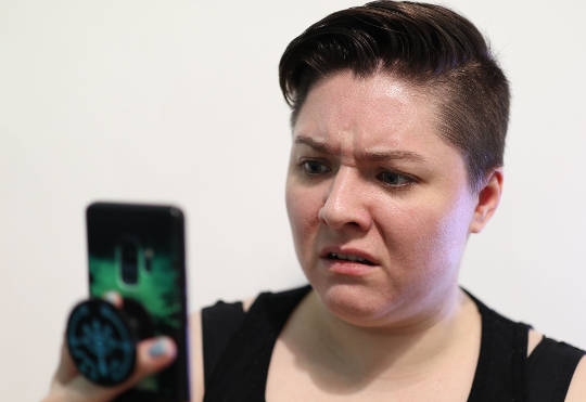 donna che guarda il suo telefono con uno sguardo di disgusto sul viso