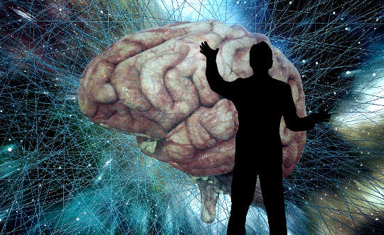 a silhouette of a man standing in front of a huge brain