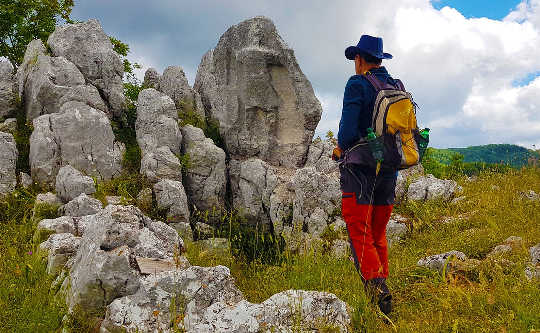 seorang pria dengan ransel berdiri di depan batu dan batu besar