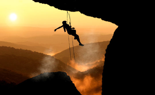 a woman mountain climbing, hanging in mid-air