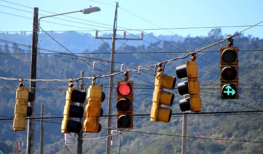 flera trafikljus - ett rött och det andra grönt med två gröna pilar uppåt och åt höger