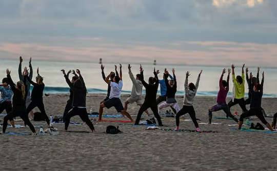 grupp människor gör yoga på stranden