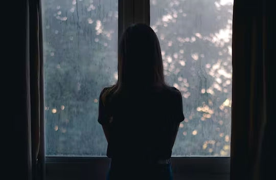 Ikkunan edessä seisovan naisen siluetti