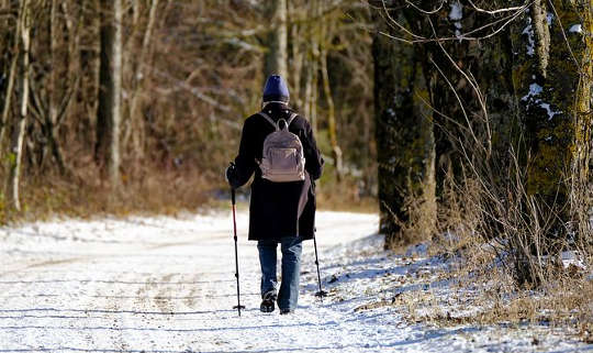 nainen kävelee lumisella tiellä