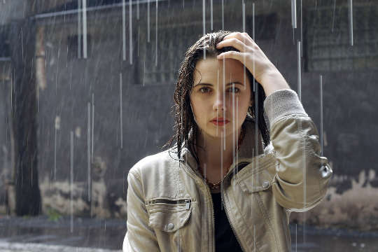 wanita muda berdiri di bawah hujan