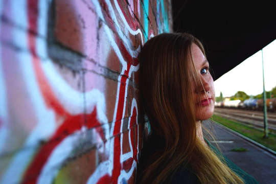 người phụ nữ trẻ hoặc cô gái đứng dựa vào bức tường graffiti