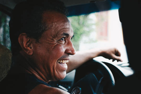 一个快乐的微笑的人在汽车的方向盘上