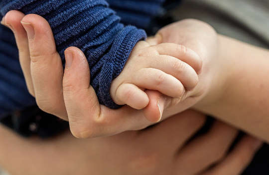 ett litet barns hand vilar i en vuxens hand