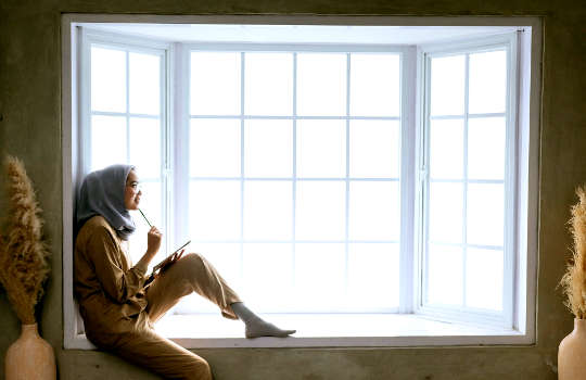 nainen istuu erkkeri-ikkunassa