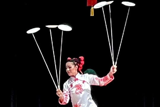 seorang wanita menyeimbangkan serangkaian piring pada tongkat