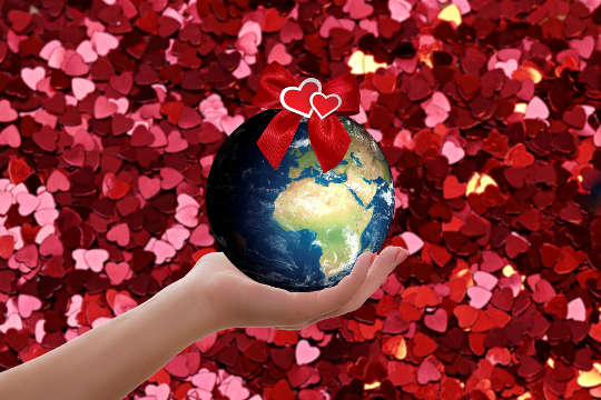 een hand die de planeet aarde vasthoudt, omringd door harten