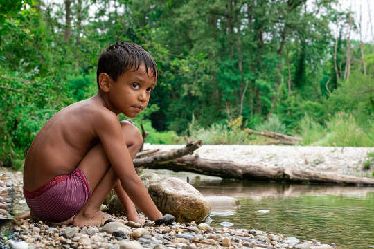 een jonge jongen op een rivieroever