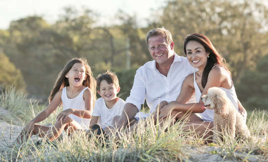 en glad familie, der sidder sammen udenfor på en eng