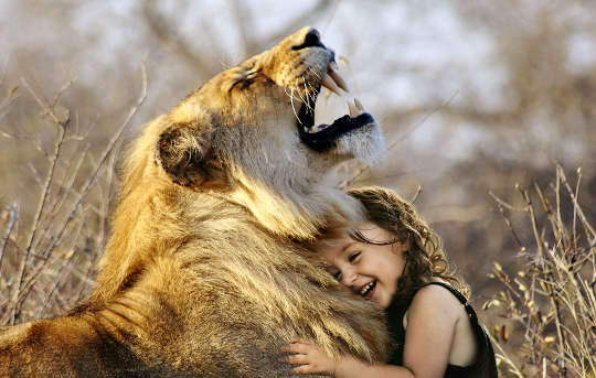 ett litet barn som kramar ett lejon som ryter