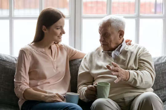 en äldre man pratar med en ung vuxen över en kopp te