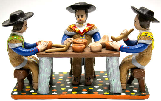 figuras de arcilla sentadas en una mesa comiendo alimentos hechos de arcilla