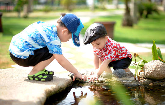 hai cậu bé đang chơi bên bờ ao