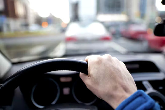 zdjęcie osoby siedzącej w samochodzie z rękami na kierownicy