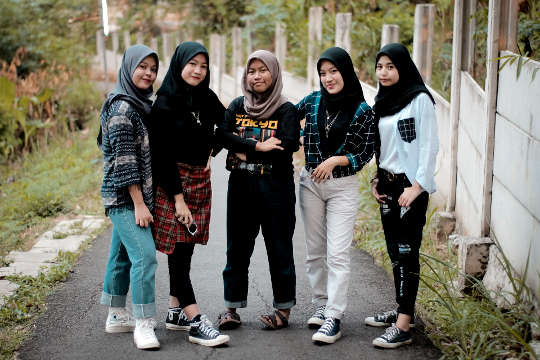 cinco mujeres jóvenes con hijabs y vestidas con ropa muy moderna, como jeans