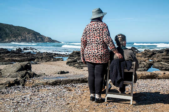 två kvinnor, en sittande, en stående och tittar ut över havet