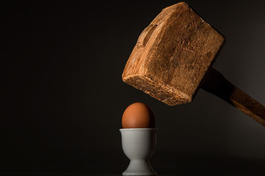 ett ägg under siktet på en hammare