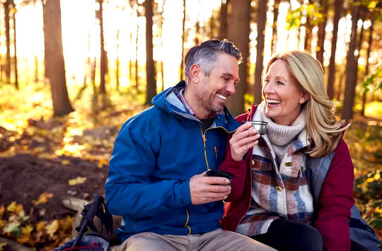 یک زن و شوهر پنجاه ساله در حال شریک خنده و یک لیوان شراب