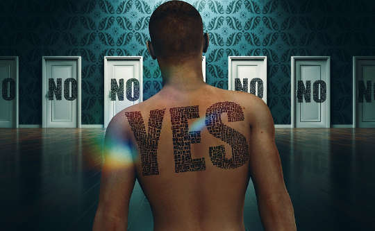 a man with the word YES on his back facing several doors with the word NO on them