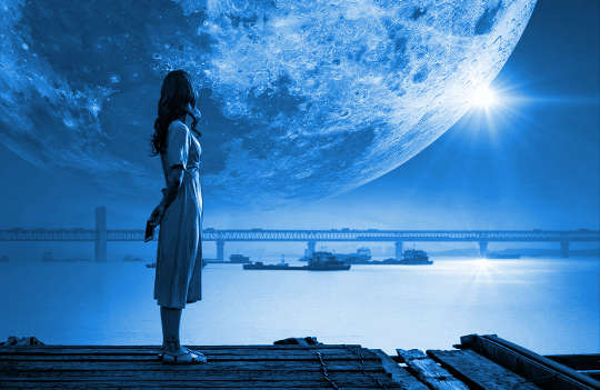 uma mulher em pé com uma enorme lua ao fundo