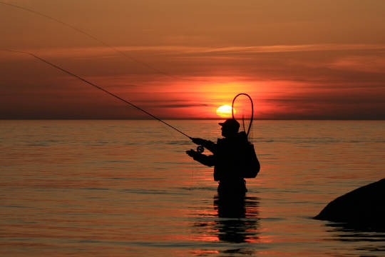 Homem dando um "intervalo" pescando ao pôr do sol