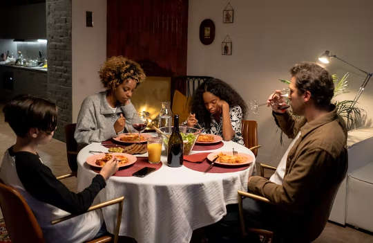 famiglia seduta attorno a un tavolo a mangiare