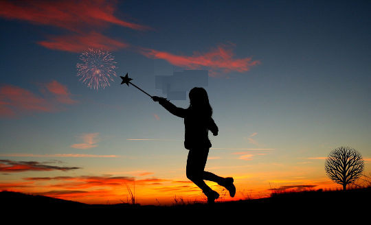 молодая девушка в поле держит перед собой волшебную палочку