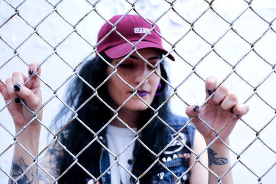 bir zincir bağlantı çitin arkasında duran bir beyzbol şapkası giyen kız