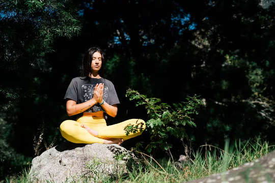 en ung kvinna som sitter utanför i lotusställning