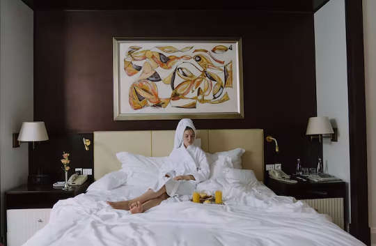 ένα άτομο που κάθεται σε ένα κρεβάτι ξενοδοχείου και παίρνει πρωινό στο κρεβάτι