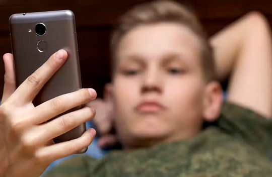 young man laying back and looking at his phone