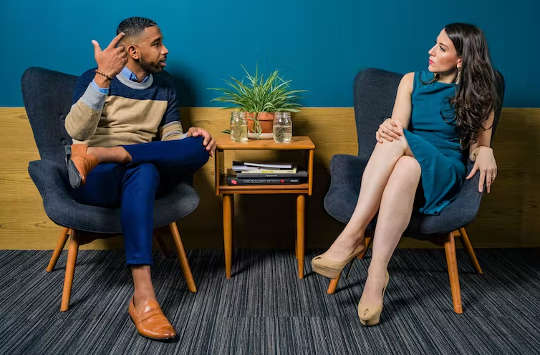 một người đàn ông và một người phụ nữ ngồi đối diện nhau nói chuyện