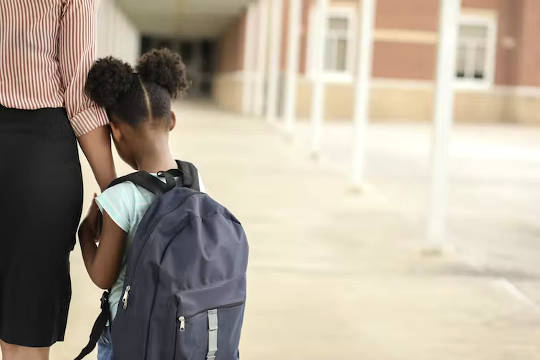 eine Mutter, die die Hand ihrer Tochter hält, als sie zur Schule zurückkehrt