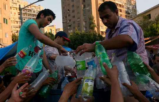 plastik içme suyu şişelerini dolduran insanlar