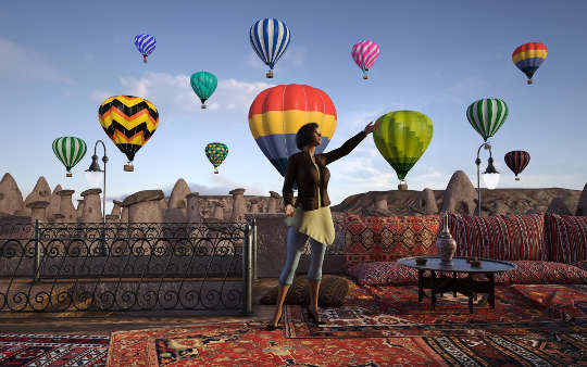 a woman standing in front of a lot of released hot air balloons