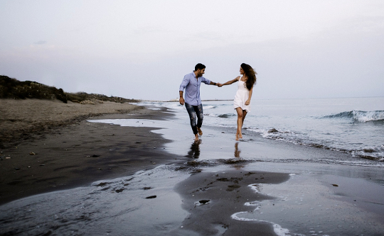 mann og kvinne som går på stranden og holder hender