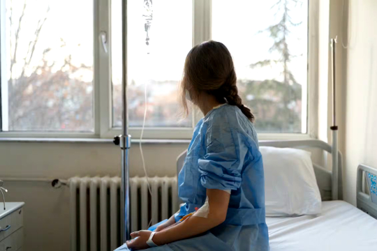 donna seduta sul lato di un letto d'ospedale