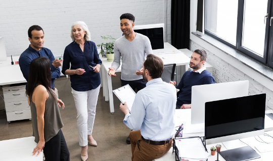 a group of workers in an office talking and smiling