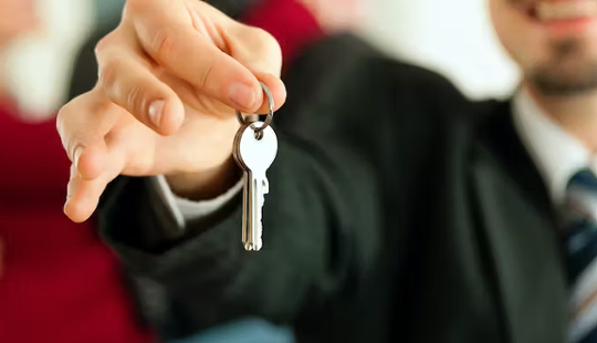 un agent immobilier tendant une clé à quelqu'un