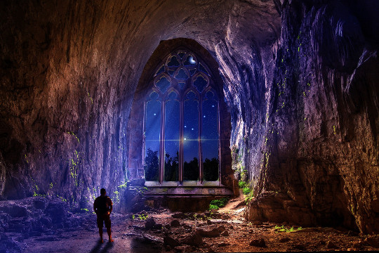 un hombre en una cueva con un gran arco que se abre a la noche y al cielo