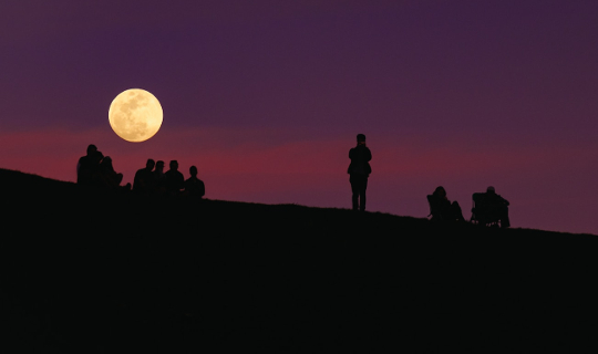 small groups of people under a full moon